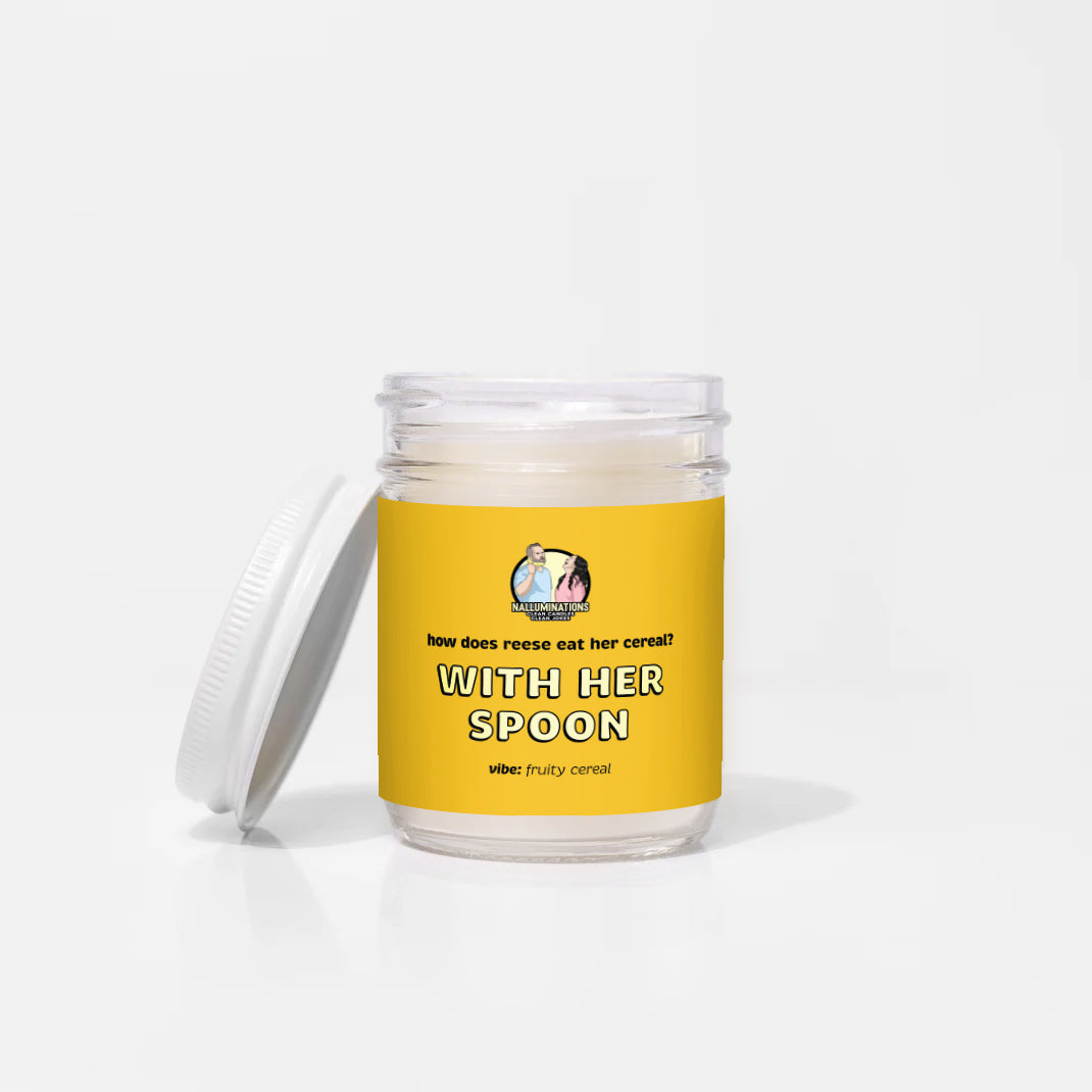 With Her Spoon – fruity cereal scented funny coconut soy candle in 6.5oz clear glass jar with white lid and yellow label, photographed on white background.