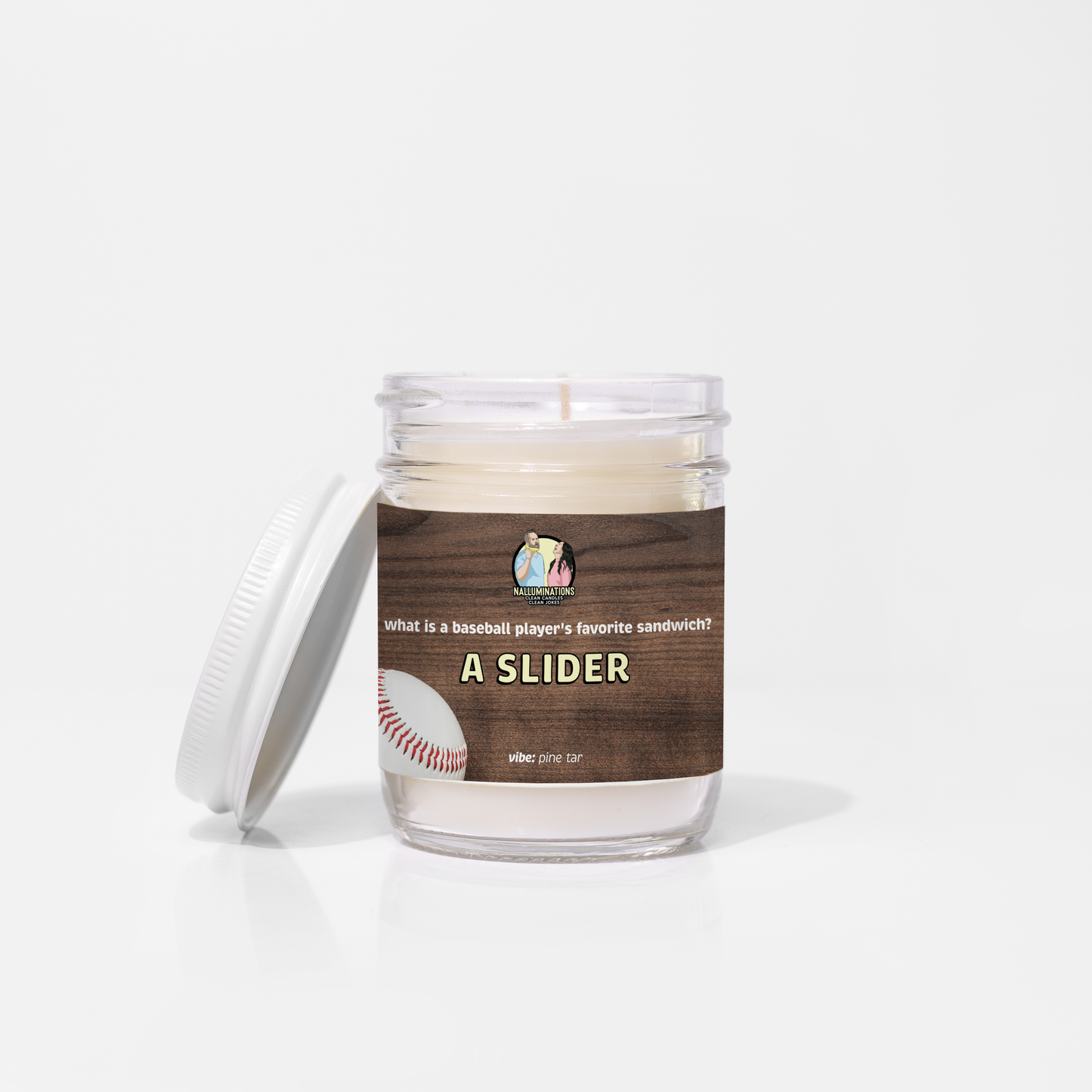 6.5oz coconut soy candle in a clear glass jar with a white lid. The wood-grain label reads “What is a baseball player’s favorite sandwich? A Slider” with a baseball graphic and scent vibe pine tar. The candle is unlit and placed against a white background.