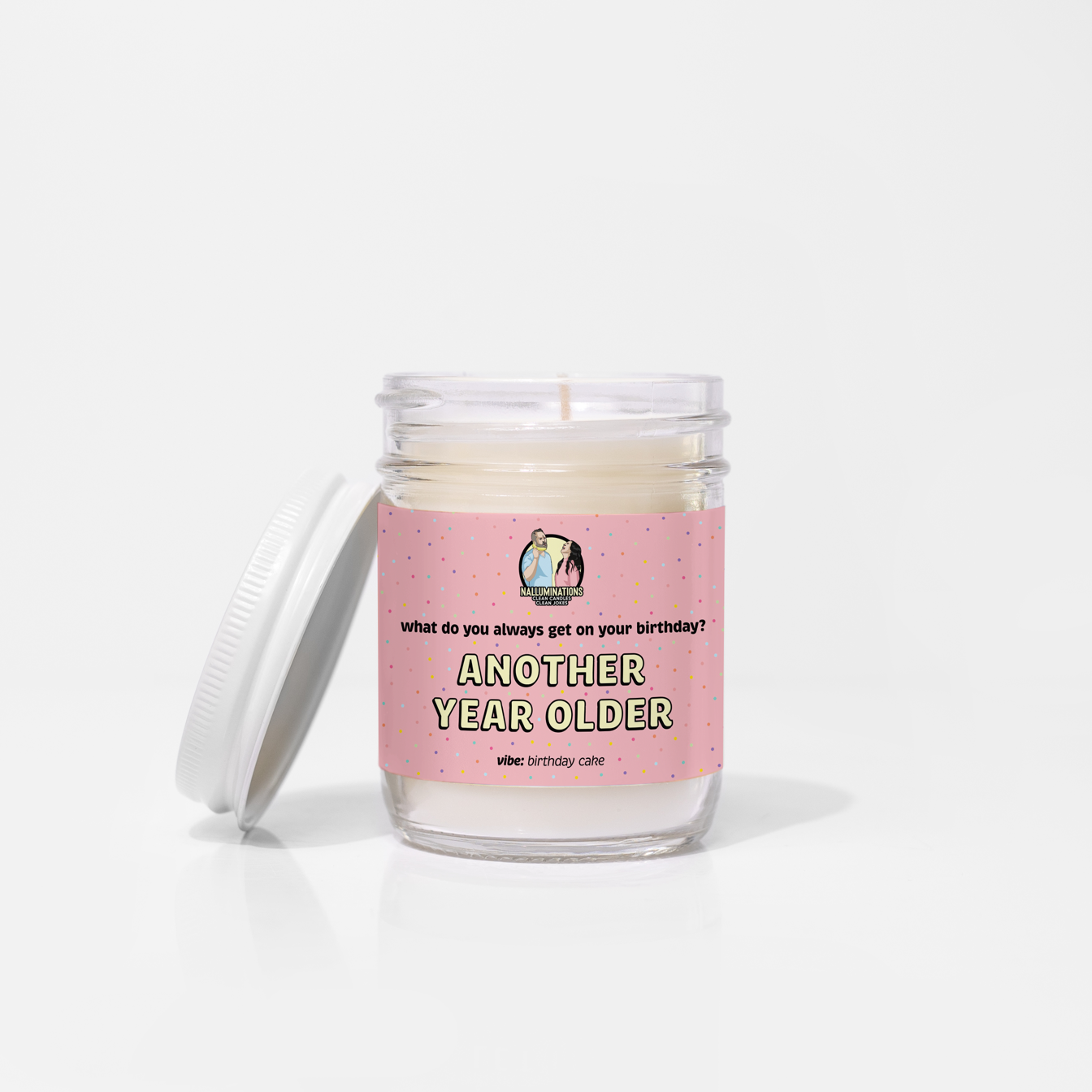 Coconut soy 6.5oz candle in a clear glass jar with white lid, labeled “Another Year Older” with a pink confetti design and birthday cake scent, unlit on a white background.