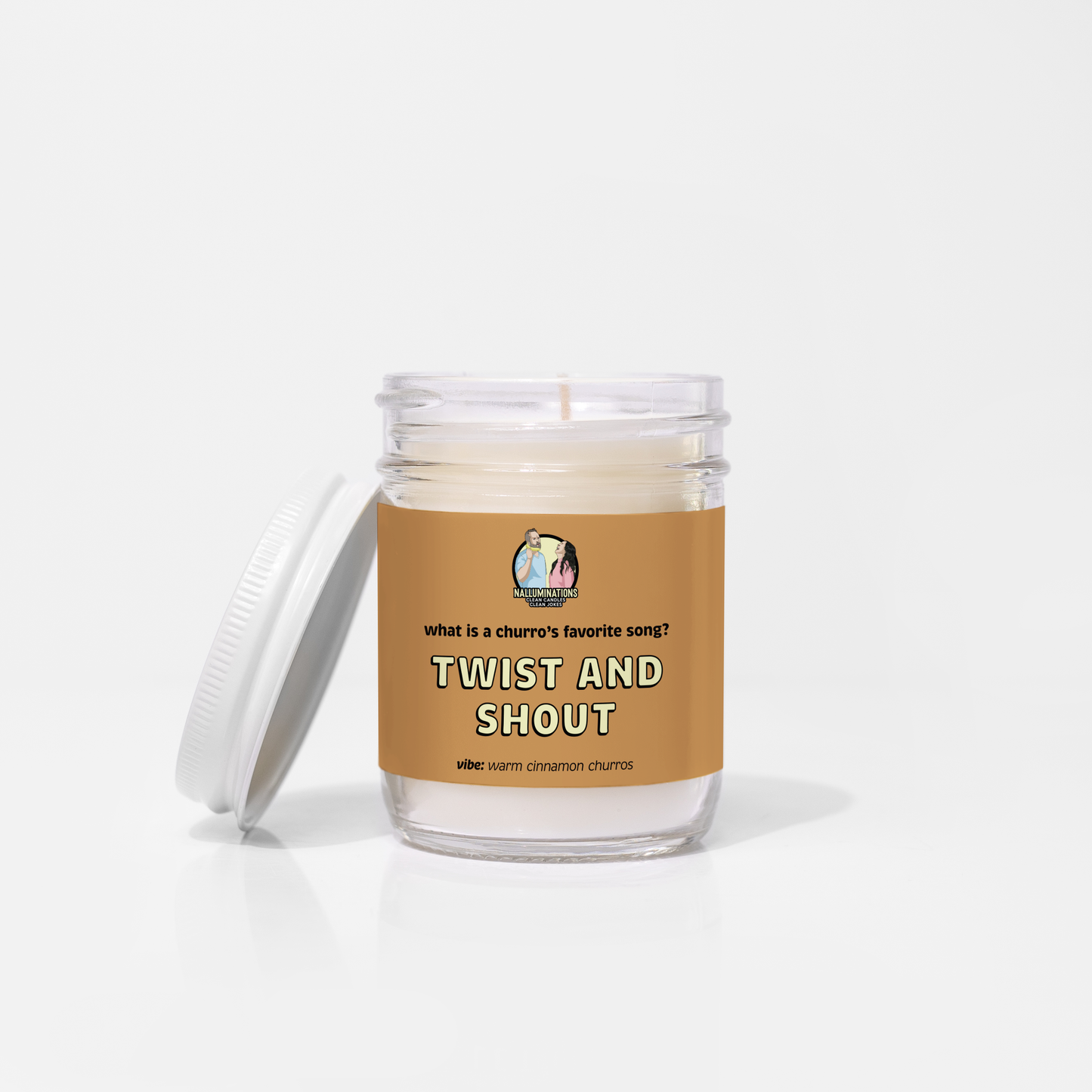 6.5oz coconut soy candle in a clear glass jar with a white lid. The brown label reads “What is a churro’s favorite song? Twist and Shout.” The scent vibe is warm cinnamon churros. The candle is unlit and placed against a white background.