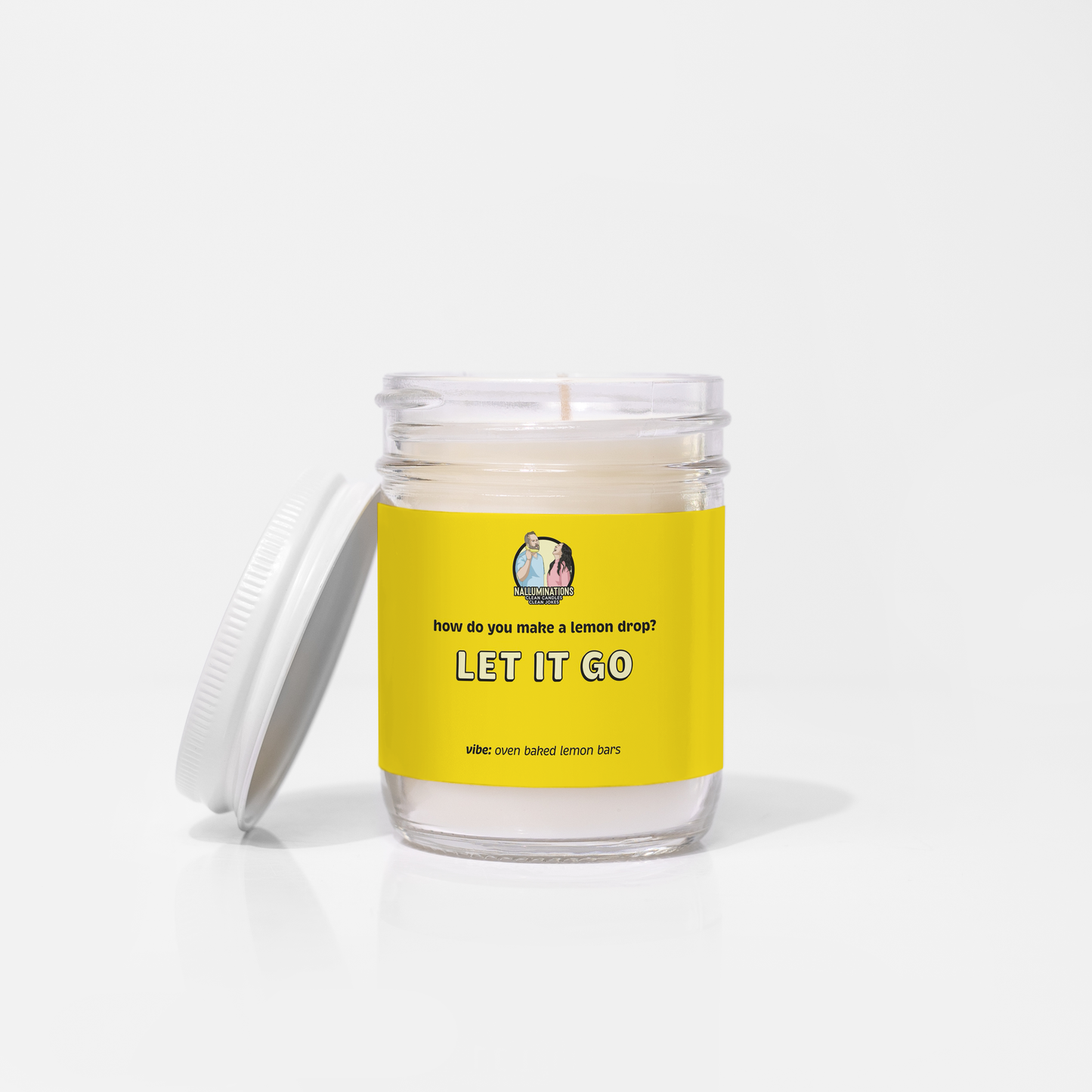 6.5oz coconut soy candle in a clear glass jar with a white lid and bright yellow label that reads “Let It Go – Oven Baked Lemon Bars.” The candle is unlit and displayed on a white background.