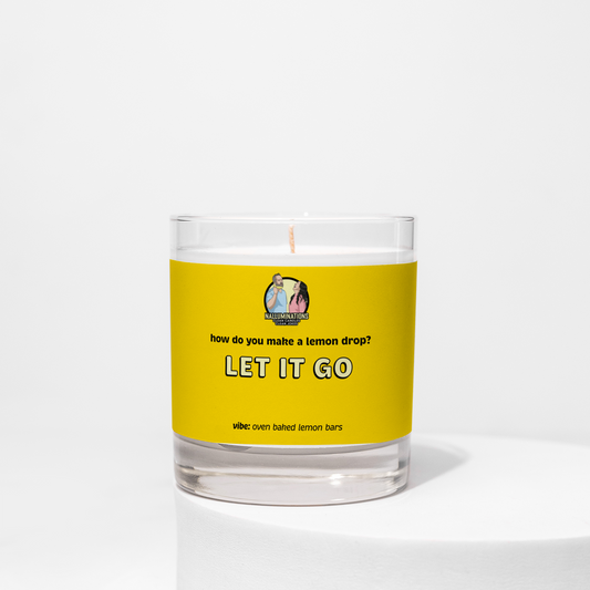 8oz coconut soy candle in a clear glass jar with a bright yellow label that reads “Let It Go – Oven Baked Lemon Bars.” The candle is unlit and displayed on a white background.