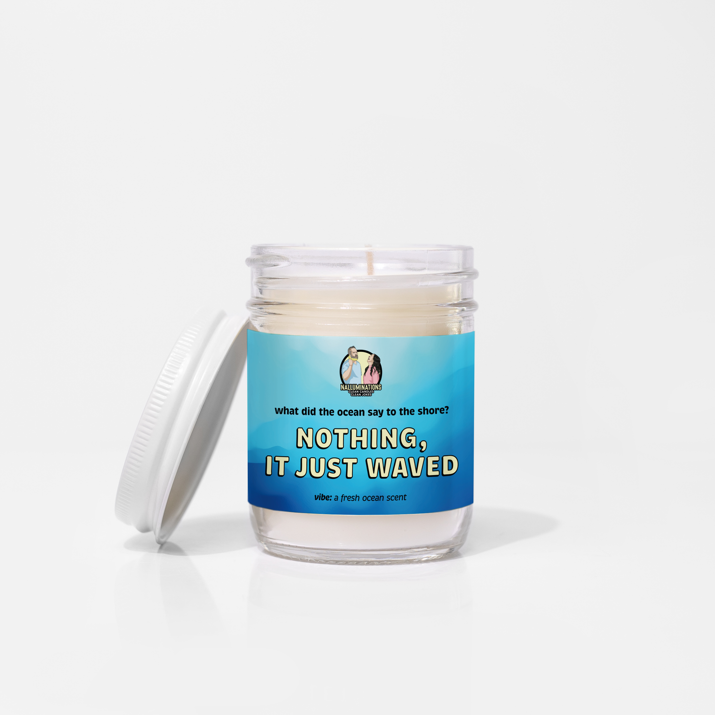 6.5oz coconut soy candle in a clear glass jar with a blue label that says “Nothing, It Just Waved.” Fresh ocean-scented candle on a white background.