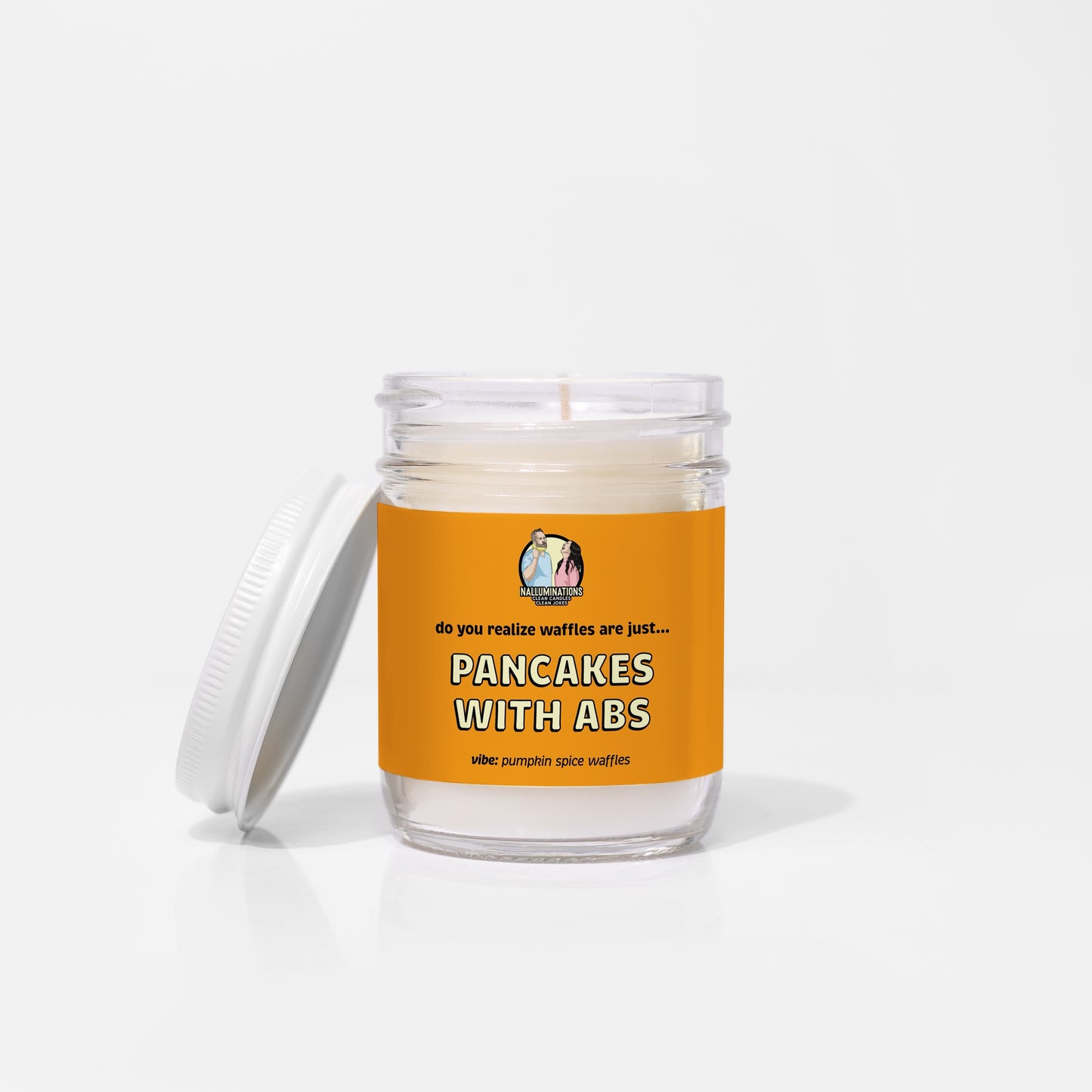 6.5oz coconut soy candle in a clear glass jar with a white lid and bright orange label that reads “Pancakes With Abs – Pumpkin Spice Waffles.” The candle is unlit and displayed on a white background.