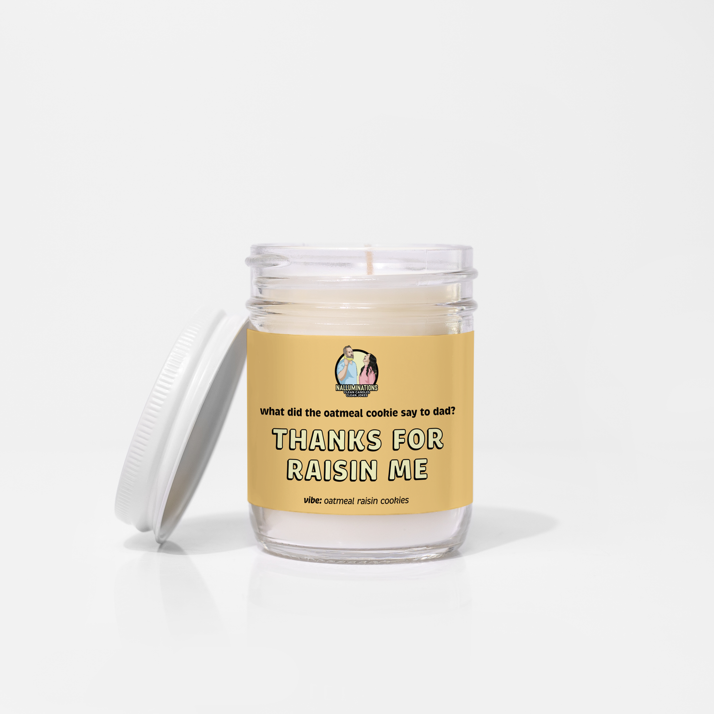 Unlit 6.5oz glass jar coconut soy candle with a white metal lid, featuring a light tan label that says: 'What did the oatmeal cookie say to dad? THANKS FOR RAISIN ME.' Scent note reads: 'vibe: oatmeal raisin cookies.' Minimalist product display.