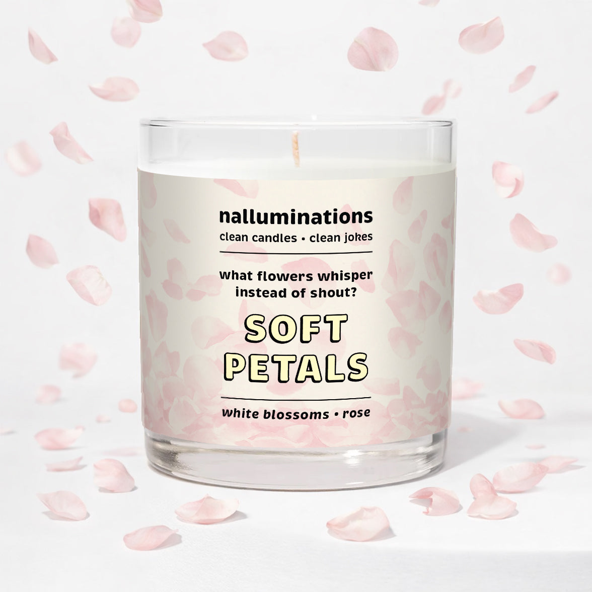Nalluminations 8oz coconut soy candle in clear glass vessel with text "soft petals" on a light background with pink flower petals.