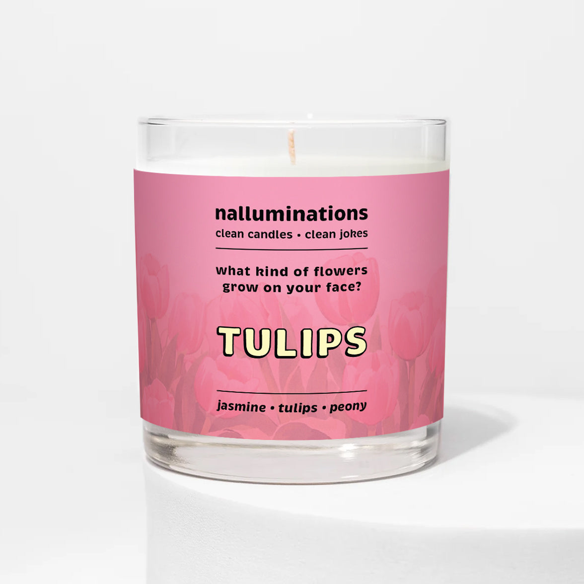 Nalluminations 8oz coconut soy candle in a clear glass vessel with a pink label featuring text and floral design on a white background