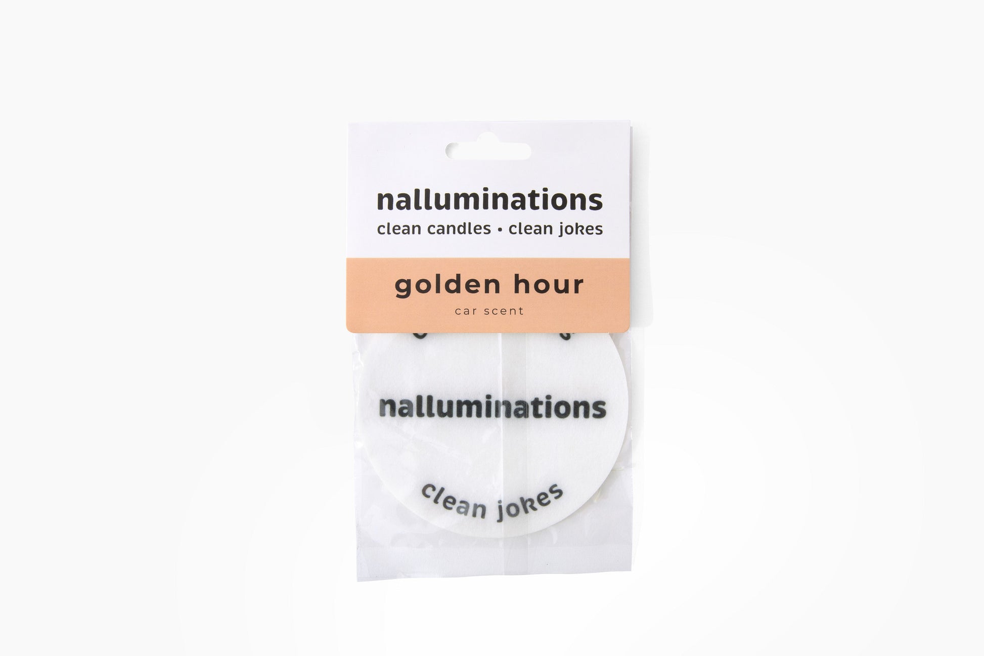 A packaged car scent disc from the brand nalluminations, labeled 'golden hour car scent'. The product consists of a white circular disc with black text, sealed in a clear plastic sleeve with a white and peach paper header card.